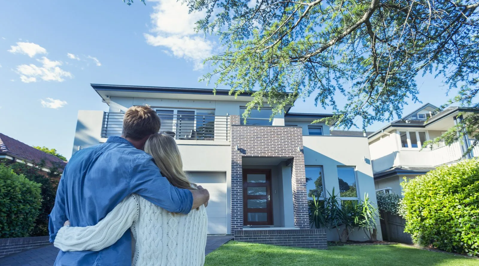 Couple standing in front of a home they are buying